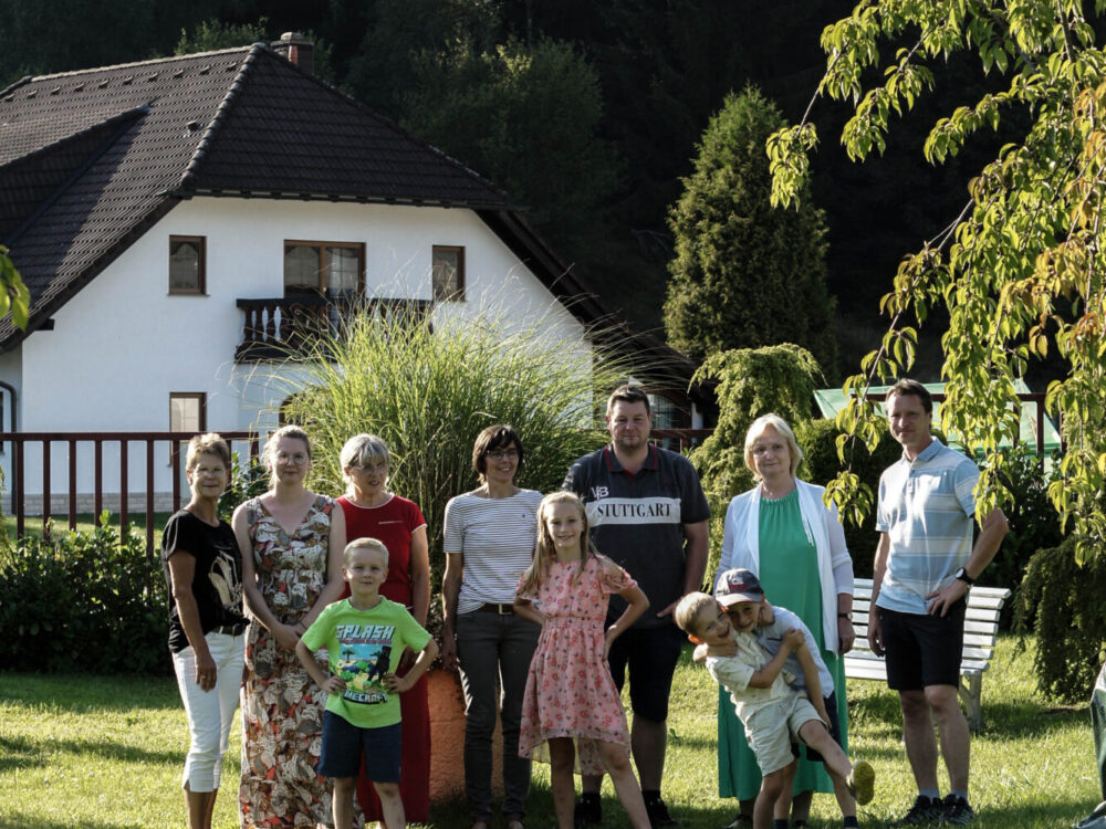 Familien mit Kindern stehen auf einer Wiese vor einem Haus in Haselbach.