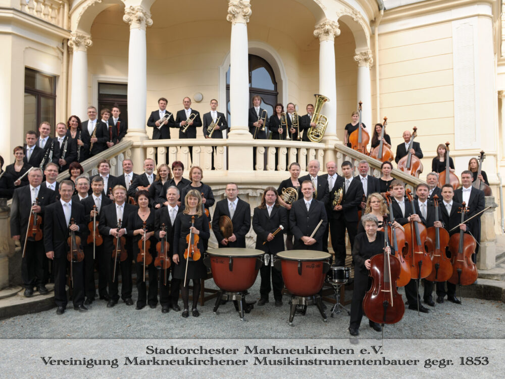 Stadtorchester Markneukirchen mit Instrumenten vor einem villenartigen Treppenaufgang mit Säulen und Ballustrade.