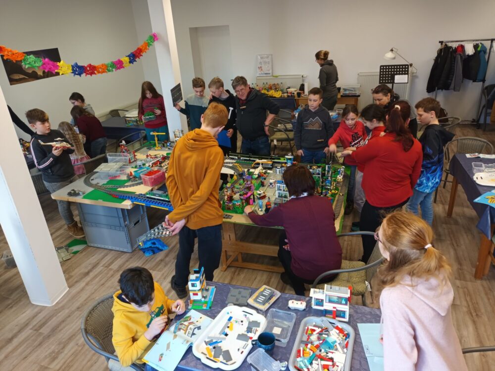 Kinder spielen an zwei Tischen mit großen Anlagen aus Legosteinen.