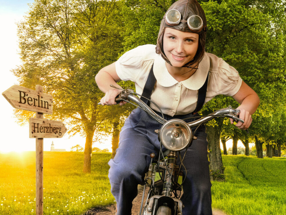 Frau mit Lederhelm auf historischem Moped auf dem Weg von Herzberg nach Berlin.